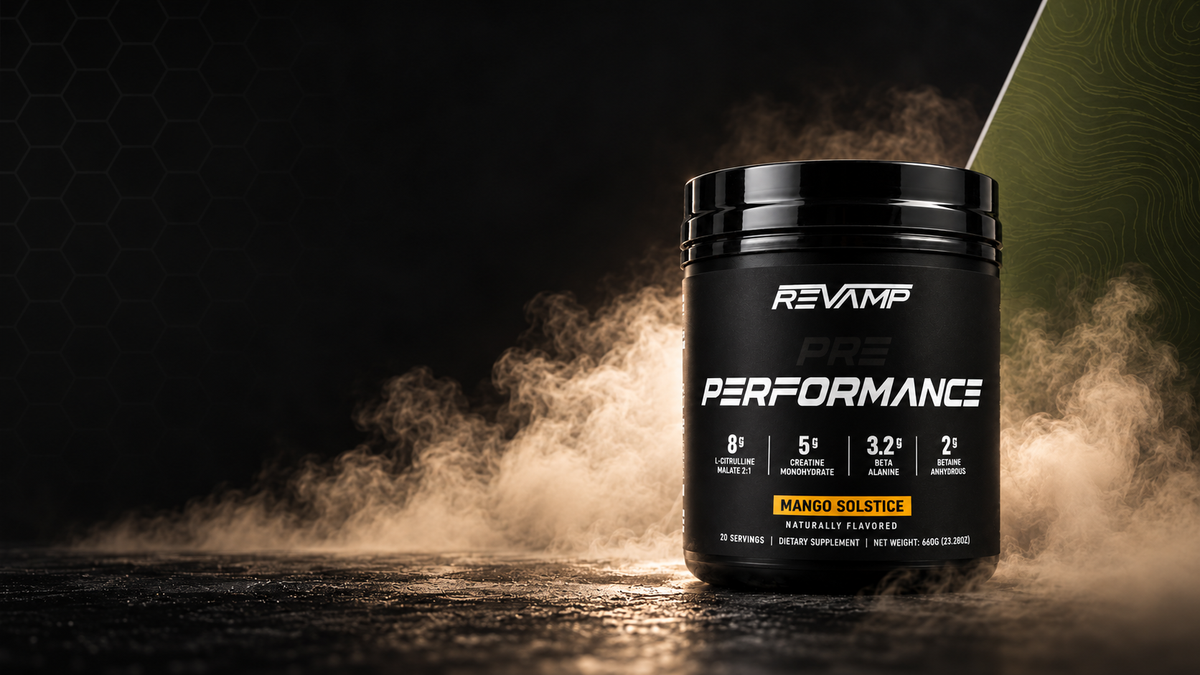 A black tub of Revamp Pre-Performance dietary supplement powder stands on a dark surface with dramatic smoke and light effects. The label reads REVAMP PRE PERFORMANCE and Mango Solstice, with supplement icons and a yellow accent band.